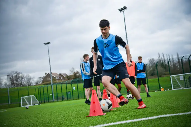 Football academy student practicing dribbling